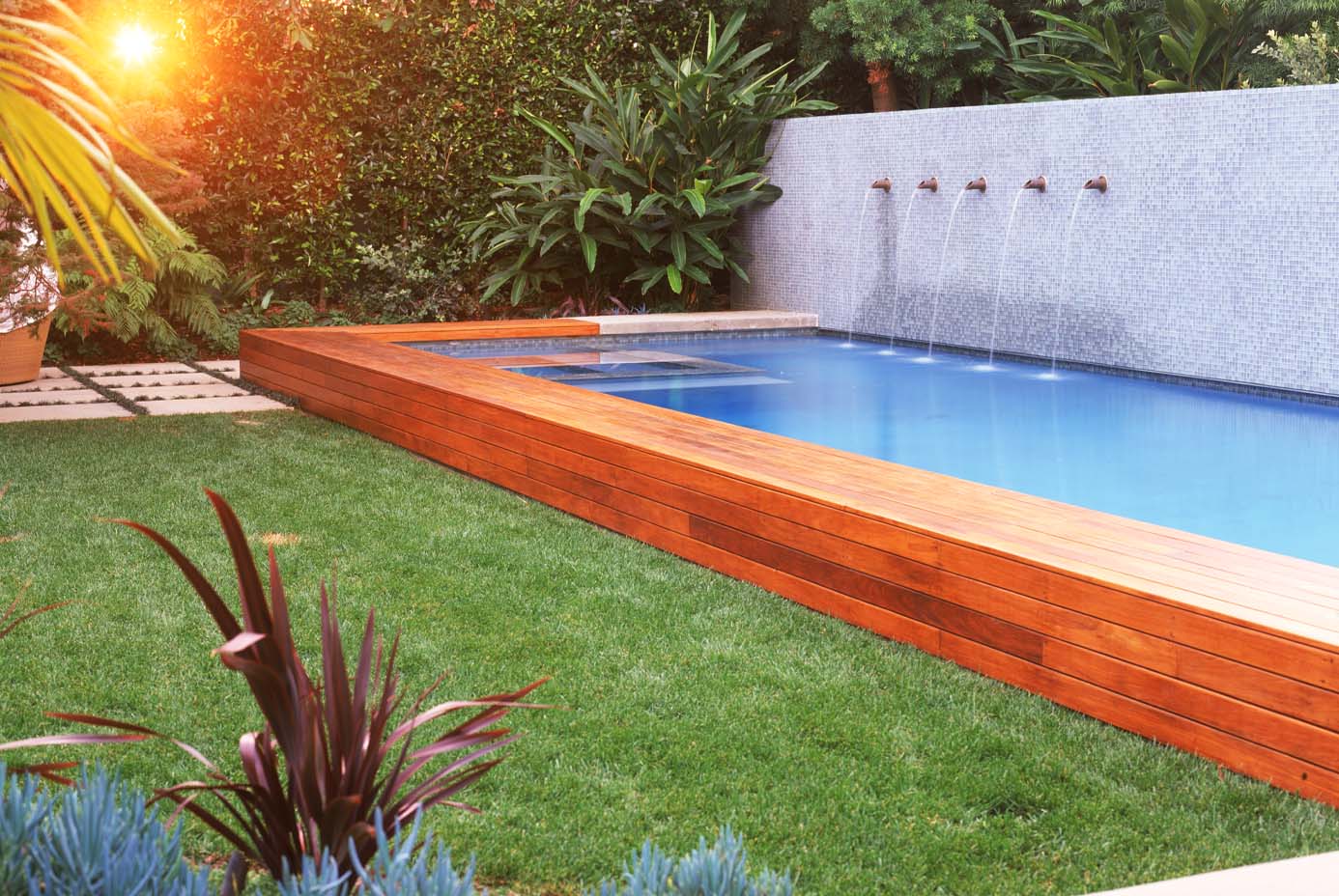 Pool garden: A wood pool surround and tiled wall contrast beautifully with a sunken lawn and exotic plantings.